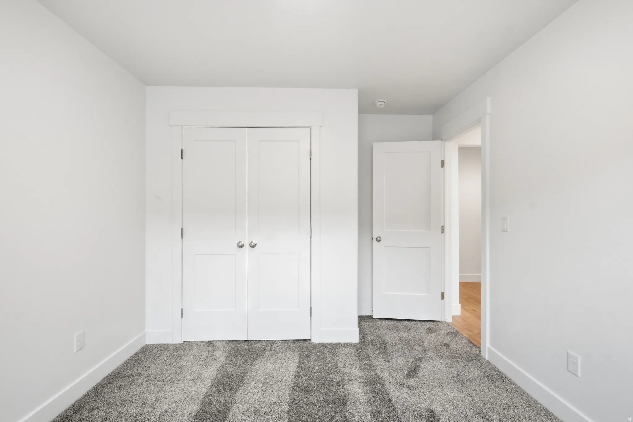 Room featuring neutral-toned walls, plush gray carpeting, and white baseboards