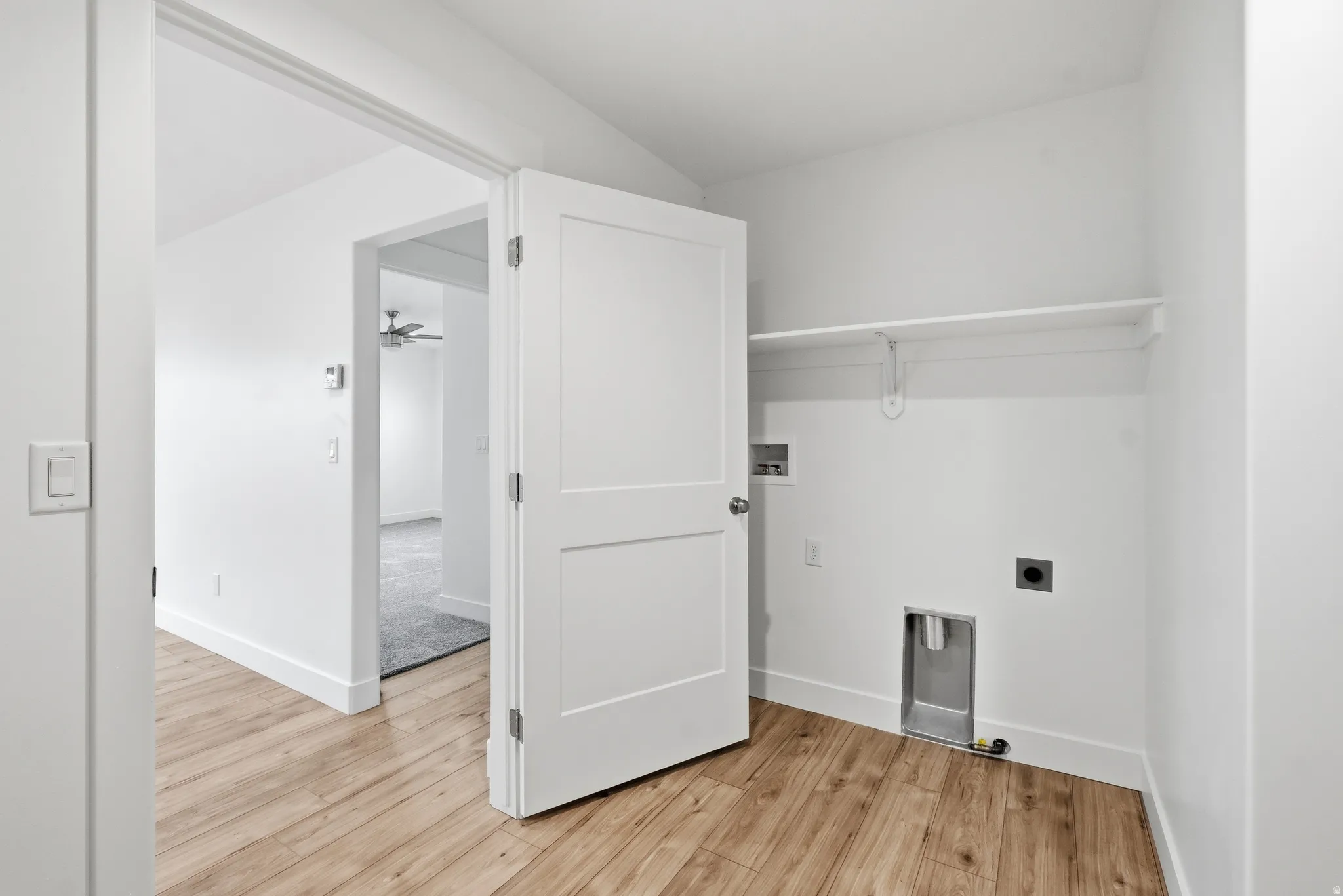 Utility area featuring wood-finish flooring, white walls, and a built-in shelf