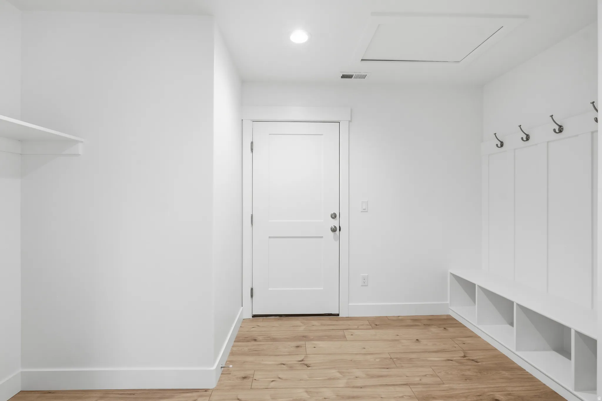 Entryway featuring wood-finish flooring, white walls, and a built-in bench with storage cubbies