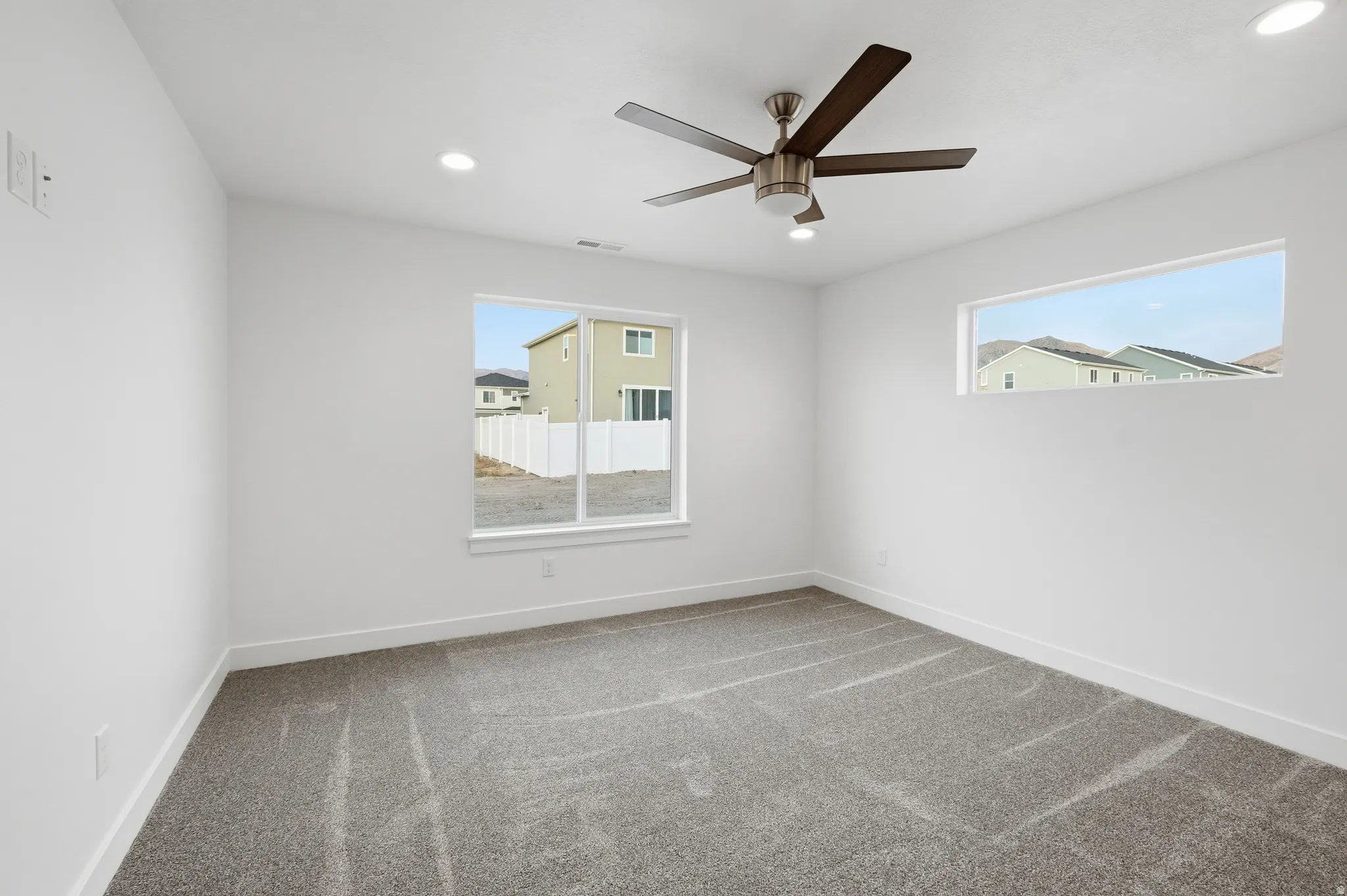 Spacious room featuring neutral carpeting, a contemporary ceiling fan, and recessed lighting
