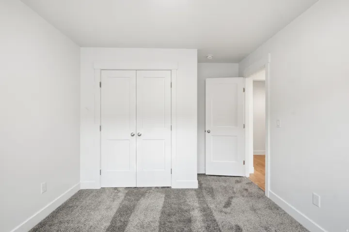 Room featuring neutral-toned walls, plush gray carpeting, and white baseboards