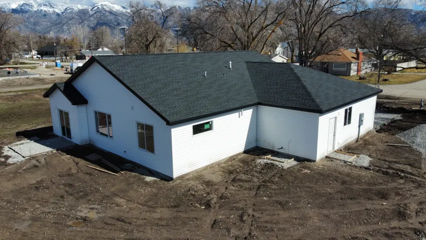 Newly constructed residence featuring white siding and a dark shingle roof