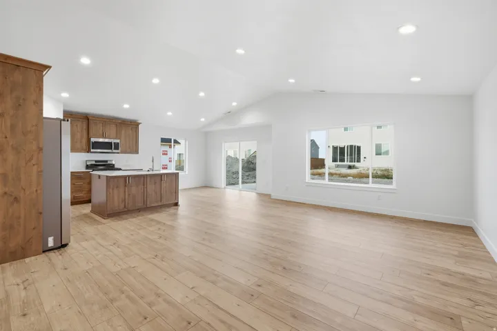 Open-concept living space featuring wood-finish flooring, a vaulted ceiling, and recessed lighting
