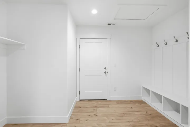 Entryway featuring wood-finish flooring, white walls, and a built-in bench with storage cubbies