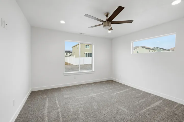 Spacious room featuring neutral carpeting, a contemporary ceiling fan, and recessed lighting