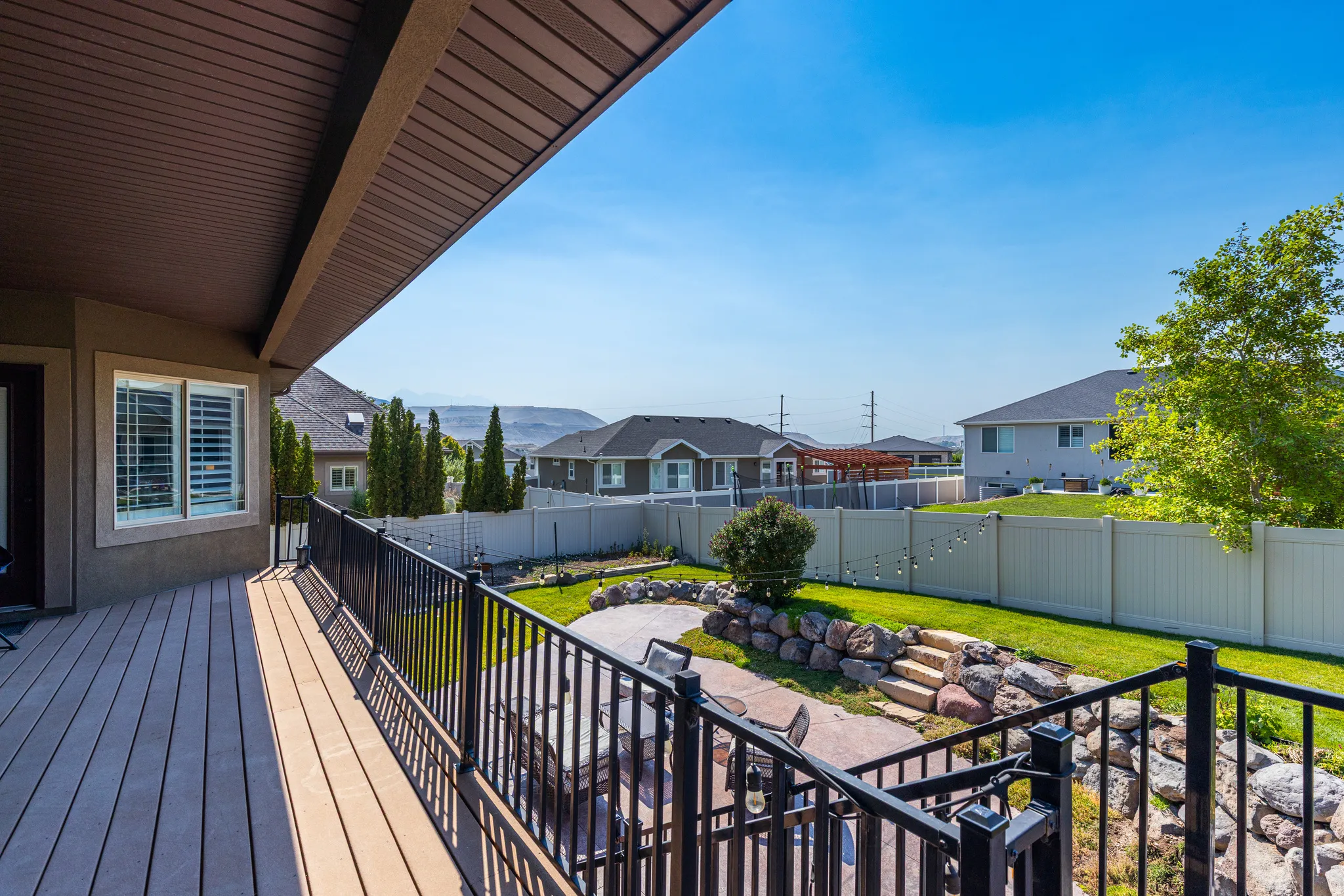 Expansive outdoor deck with composite decking and a black metal railing, featuring an integrated patio cover