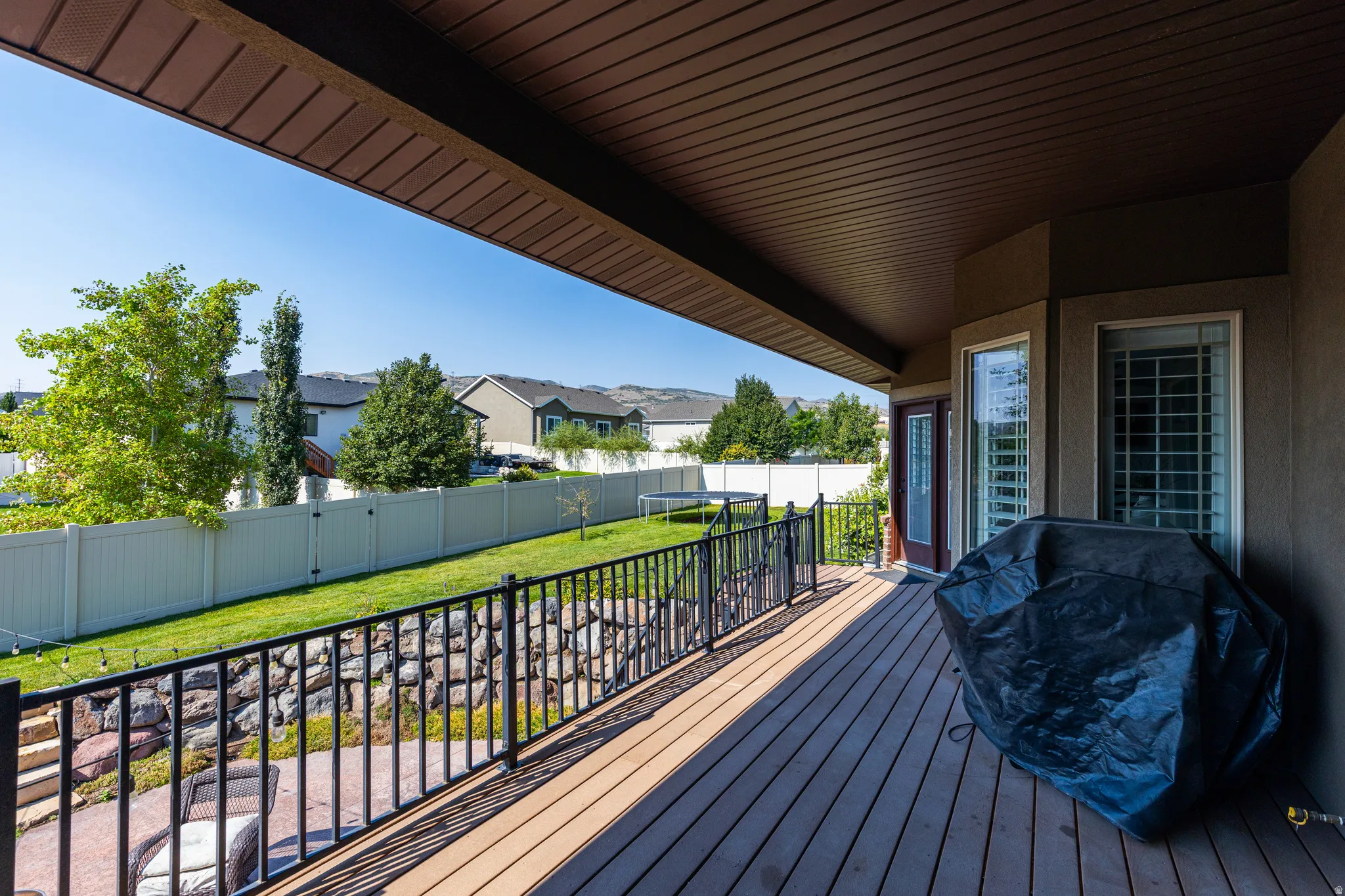 Spacious composite deck featuring premium wood-finish decking, black metal railings, and covered overhead structure