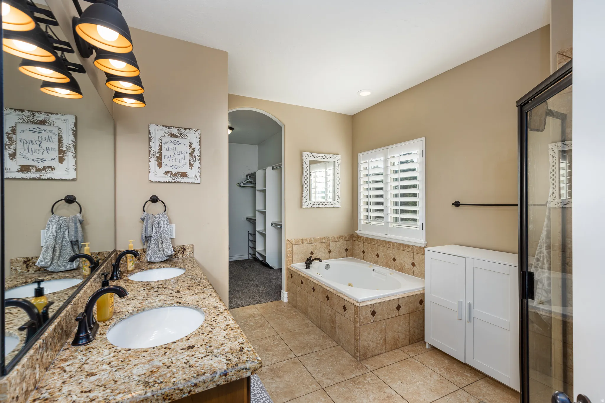 Bathroom featuring a dual vanity with granite-finish countertops, undermount sinks, and matte black fixtures