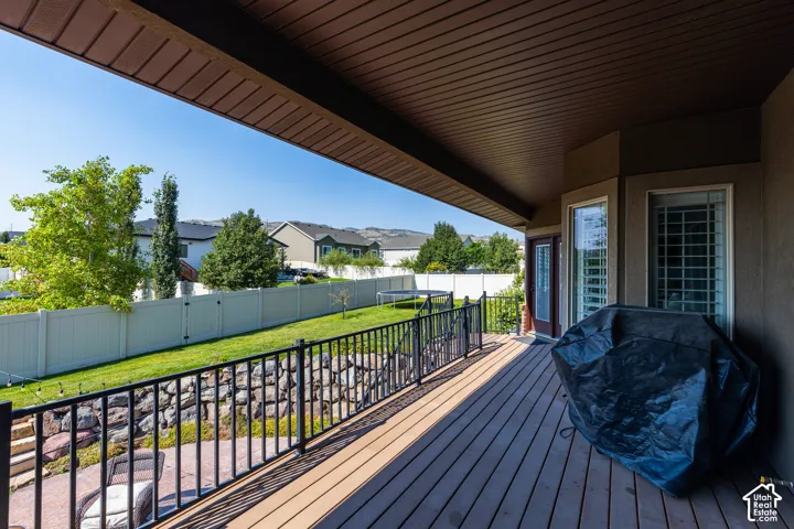Spacious composite deck featuring premium wood-finish decking, black metal railings, and covered overhead structure