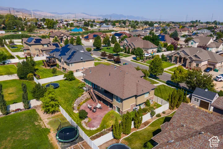 Landscaped backyard featuring a terraced paver patio, a white privacy fence, and mature trees