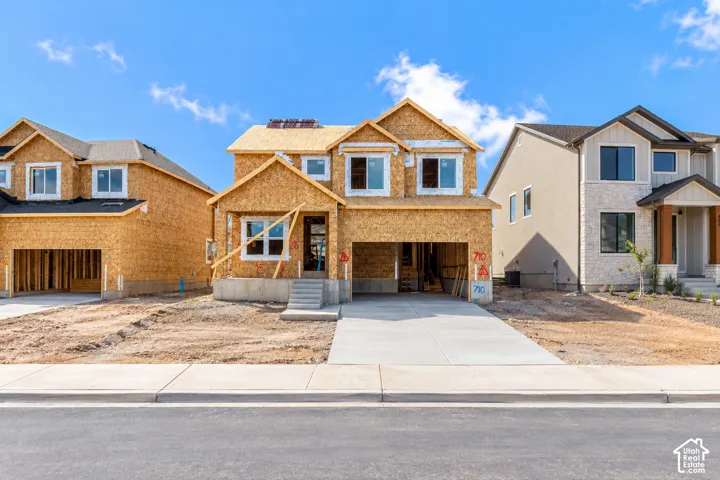 New construction framing with a two-story design, attached garage, and concrete driveway