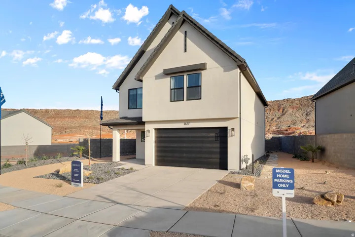Contemporary two-story residence featuring a light-toned stucco exterior and a dark, gabled roof