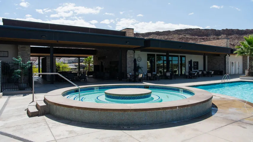 Outdoor pool area featuring a circular spa with mosaic tiling, an adjacent swimming pool, and concrete decking