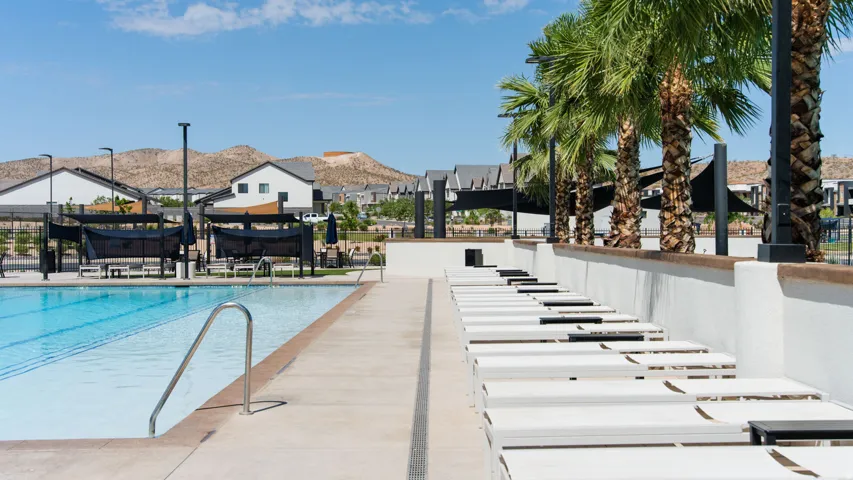 Resort-style community pool and spa area featuring Olympic-length lap lanes, sun loungers, mature palm trees, and mountain vistas