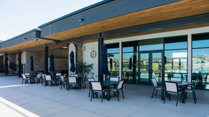 Expansive outdoor patio area featuring a concrete surface, overhead wood-finish soffits, and a stone accent wall