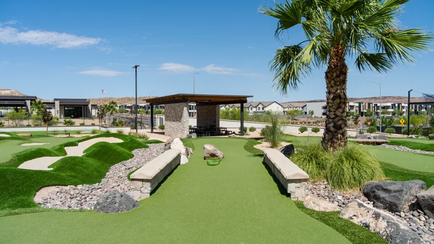 Miniature golf course featuring artificial turf greens and roughs, rock landscaping elements, and a shaded outdoor pavilion
