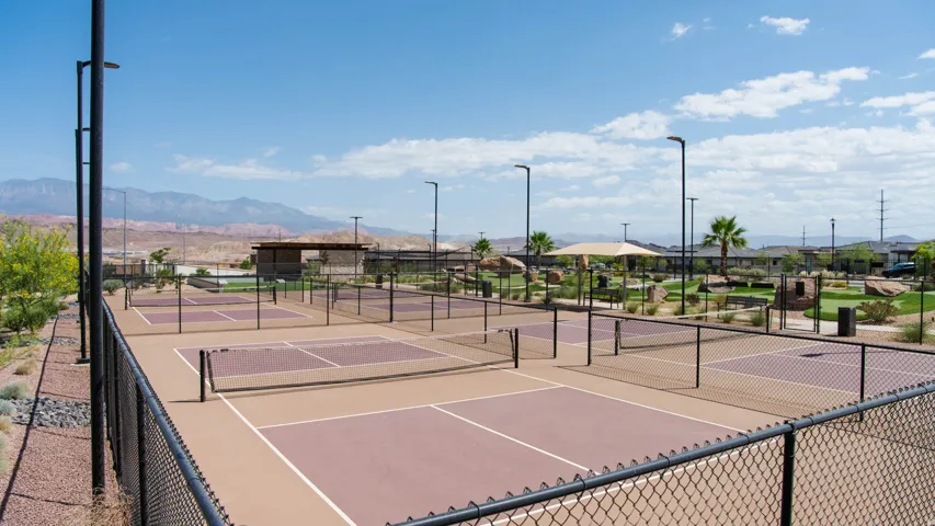 Multiple pickleball courts with perimeter fencing, integrated lighting, and a desert landscape backdrop