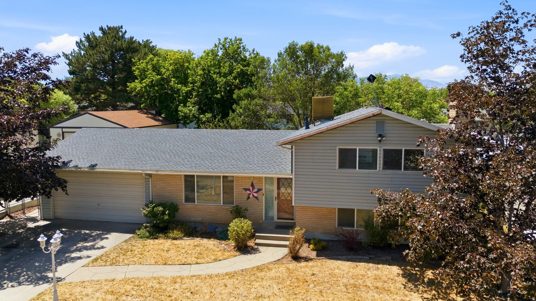 Split-level residence featuring a two-car garage, brick and siding exterior, and a central entryway with concrete steps
