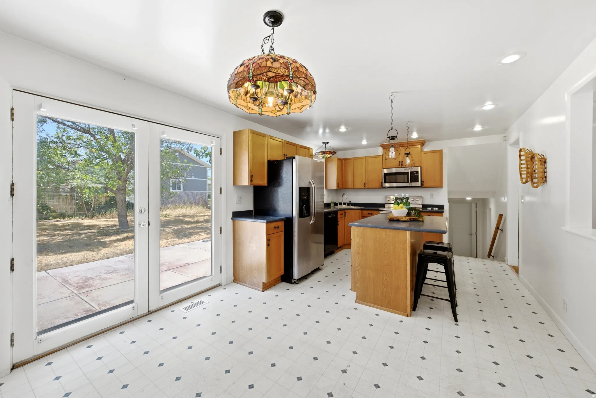 Kitchen featuring light wood cabinetry, a central island with a dark countertop, stainless steel appliances, and recessed lighting