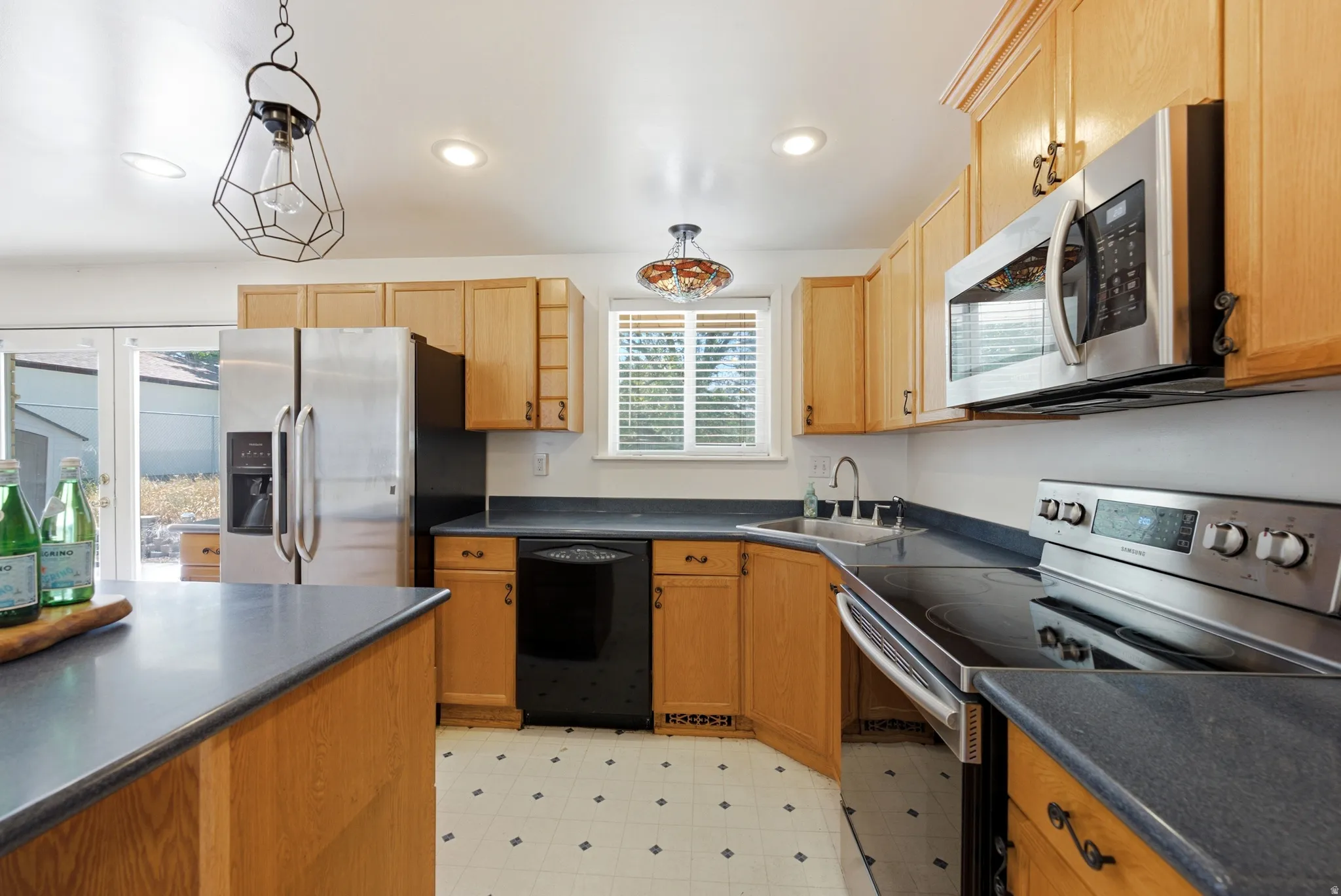 Kitchen featuring wood cabinetry, newer stainless steel appliances, dark countertops, and a double-basin sink