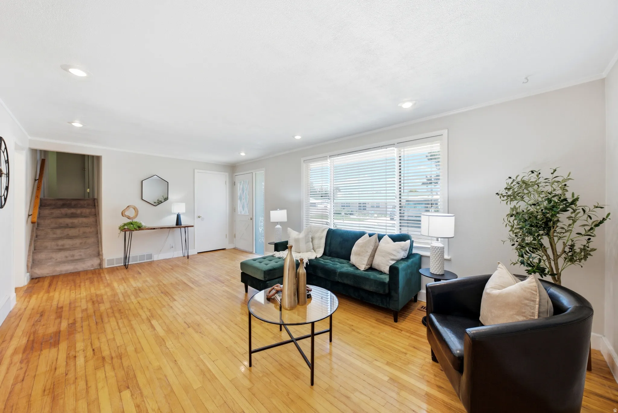 Spacious living area featuring polished wood flooring, recessed lighting, and large windows with blinds