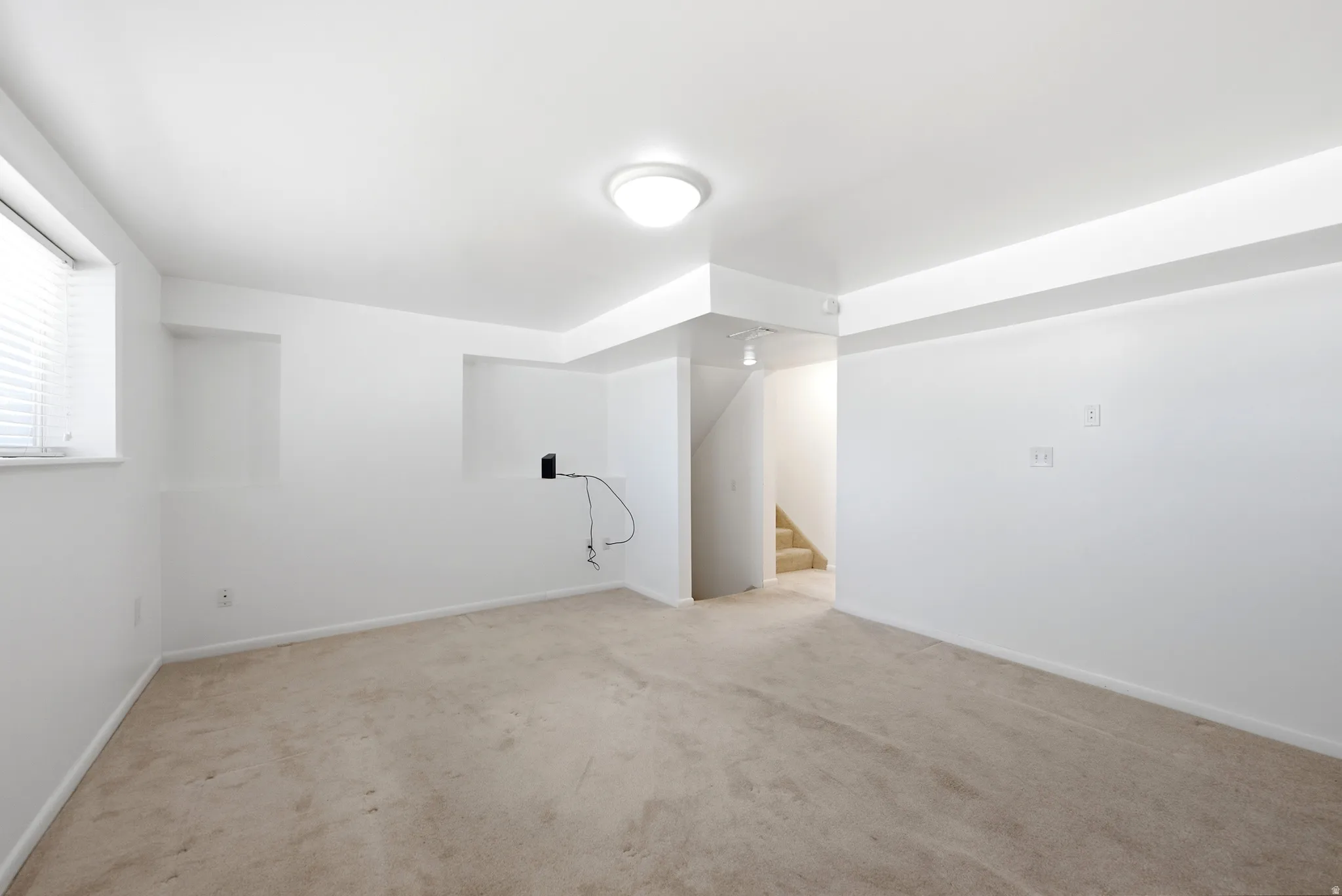 view family room into the hall and staircase,  recessed wall niches, and a ceiling-mounted light fixture