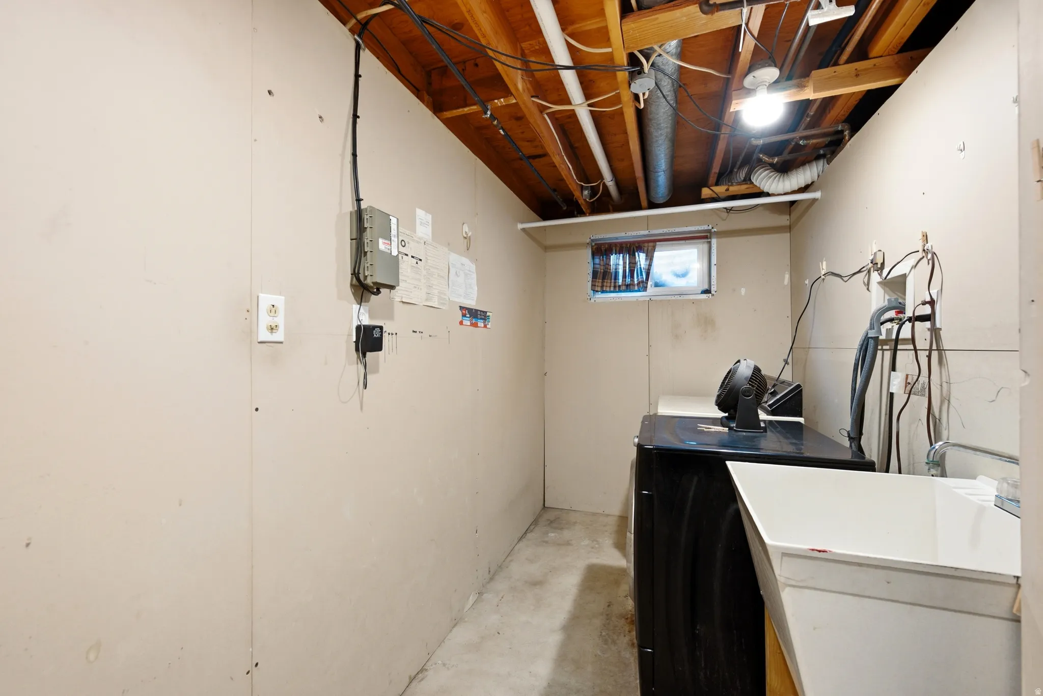 Utility area featuring concrete flooring, exposed ceiling beams, and a small casement window