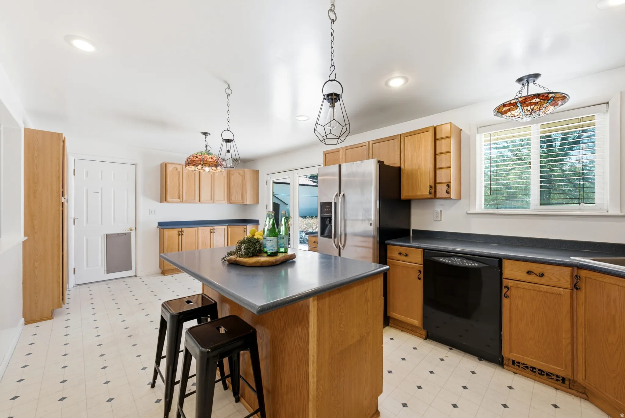 Spacious kitchen featuring an island with countertop seating, wood-finish cabinetry, newer appliances, and patterned flooring