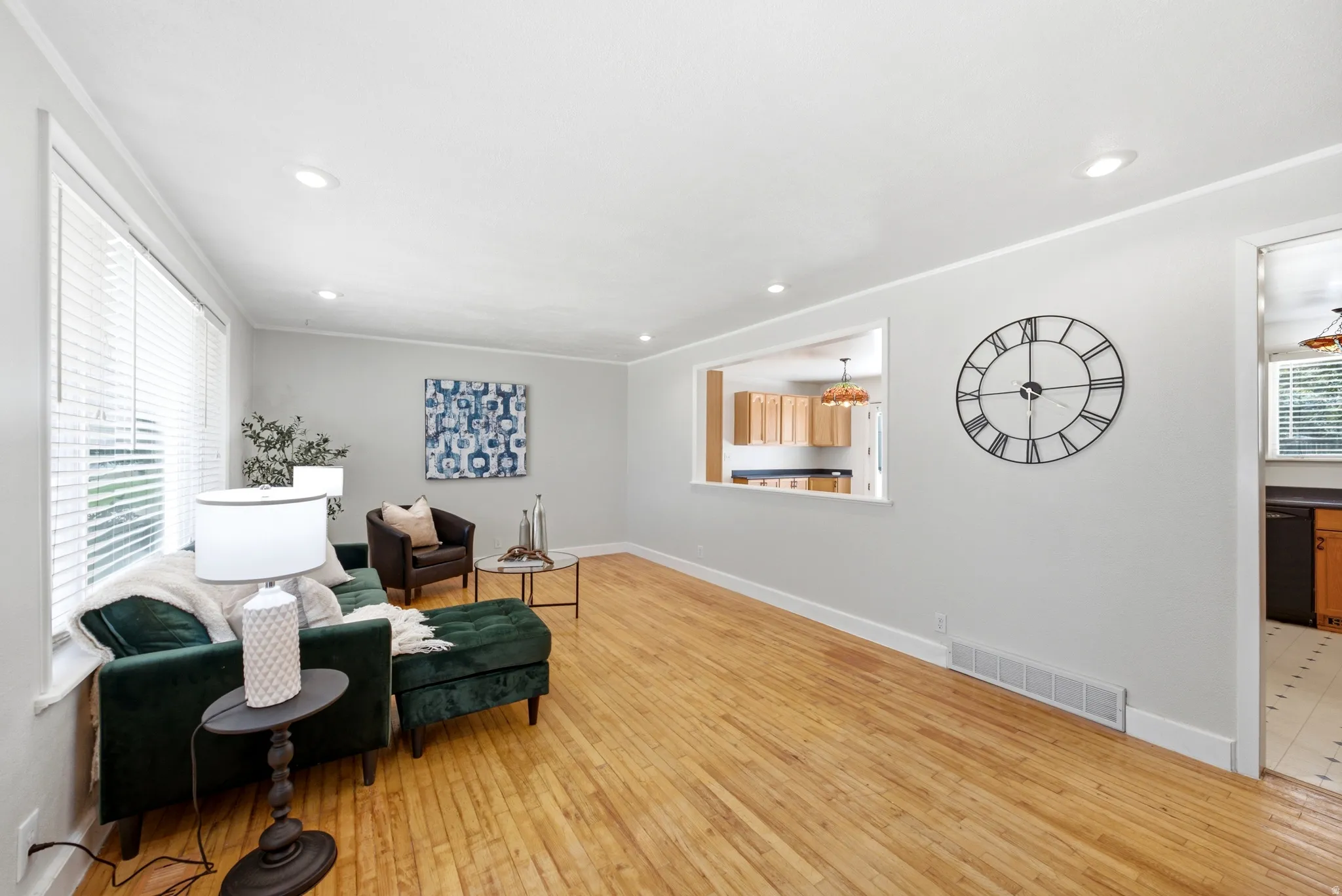 Living area featuring wood-finish flooring, recessed lighting, and a pass-through window to the kitchen