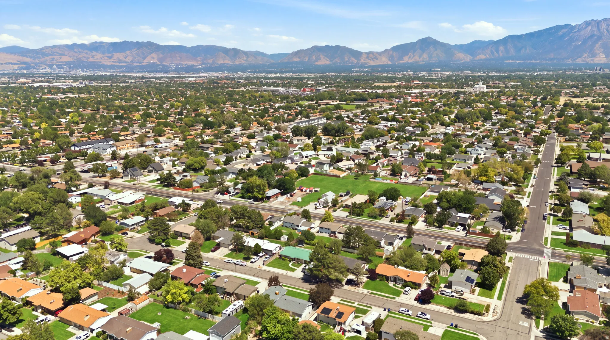 Expansive aerial perspective showcasing a residential area with varied housing styles, mature trees.