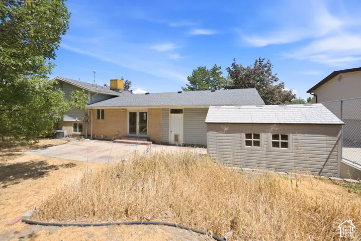 Rear exterior featuring a concrete patio, brick and siding facade, and a storage shed
