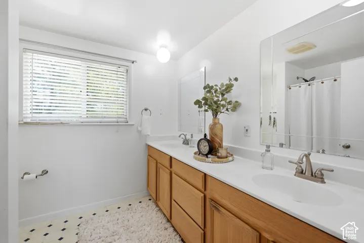 Double vanity with light wood-finish cabinetry, white countertops, and dual oval sinks