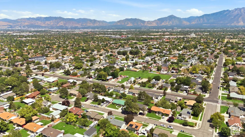 Expansive aerial perspective showcasing a residential area with varied housing styles, mature trees.