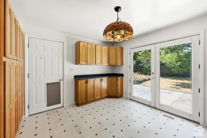 Kitchen area featuring light wood cabinetry, black countertops, and patterned tile flooring