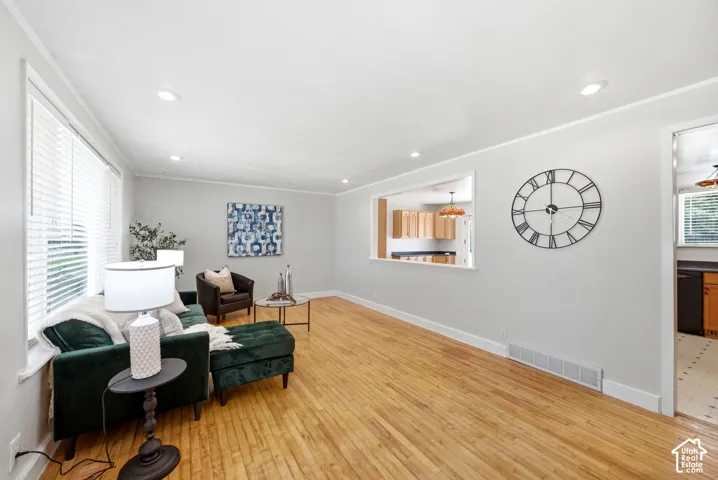 Living area featuring wood-finish flooring, recessed lighting, and a pass-through window to the kitchen