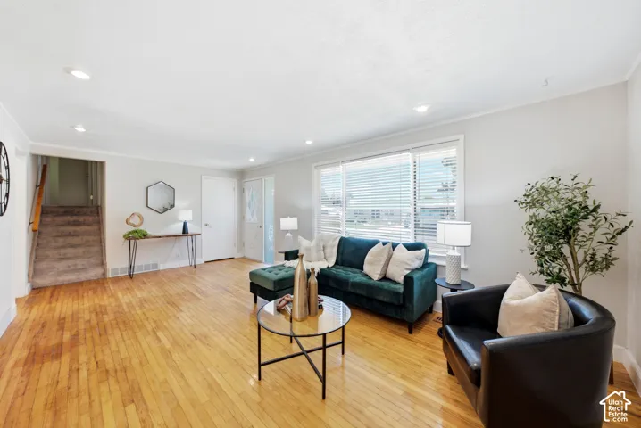 Spacious living area featuring polished wood flooring, recessed lighting, and large windows with blinds