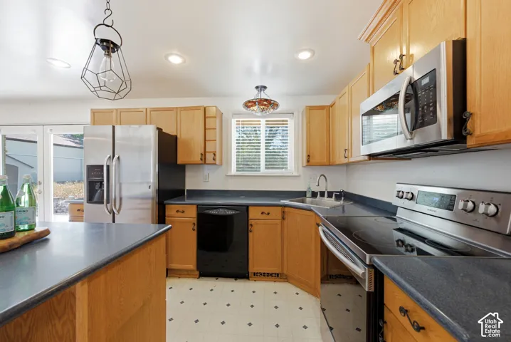 Kitchen featuring wood cabinetry, newer stainless steel appliances, dark countertops, and a double-basin sink