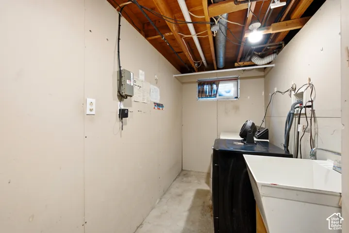 Utility area featuring concrete flooring, exposed ceiling beams, and a small casement window