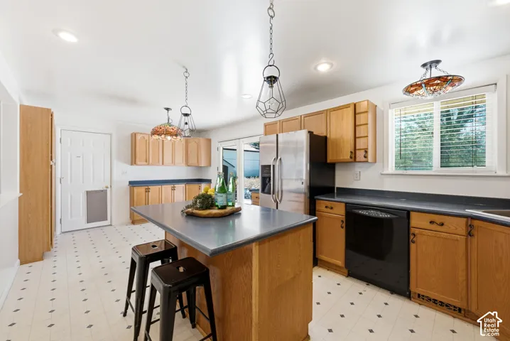 Spacious kitchen featuring an island with countertop seating, wood-finish cabinetry, newer appliances, and patterned flooring