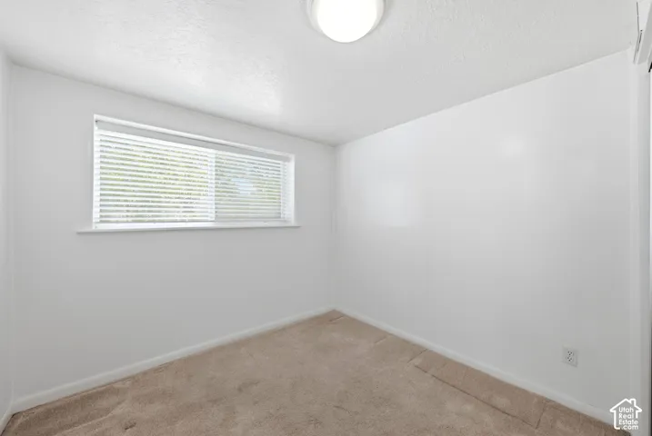 Neutral-toned wall-to-wall carpeting complements the white walls and ceiling