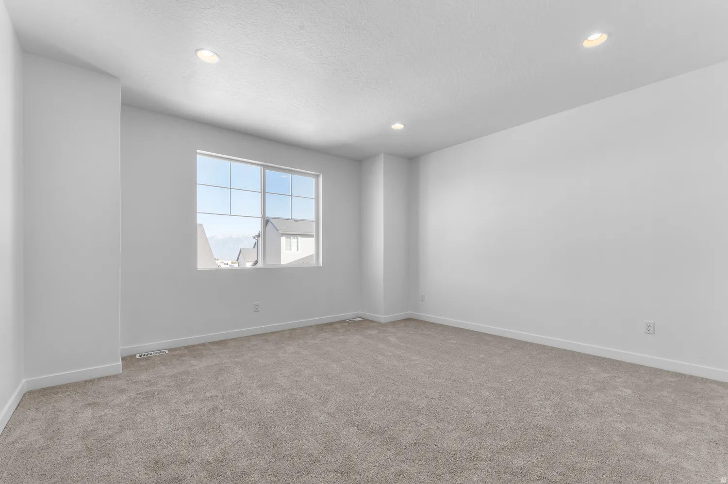 Recessed lighting, large window with grid pattern, neutral-toned carpeting, and painted walls