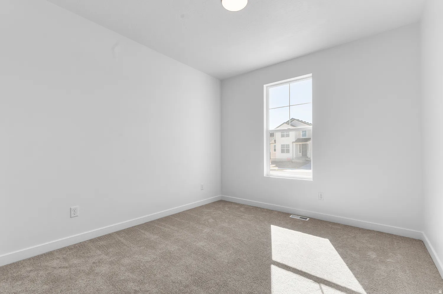 Carpeted room with white walls, a single window, and a flush-mount ceiling light fixture