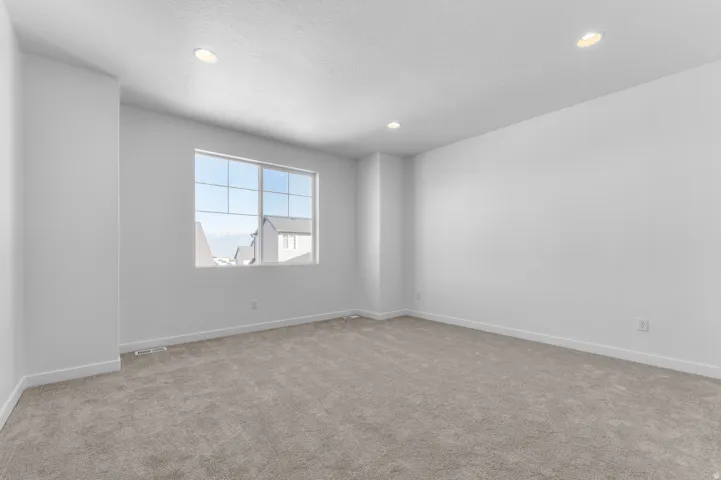 Recessed lighting, large window with grid pattern, neutral-toned carpeting, and painted walls