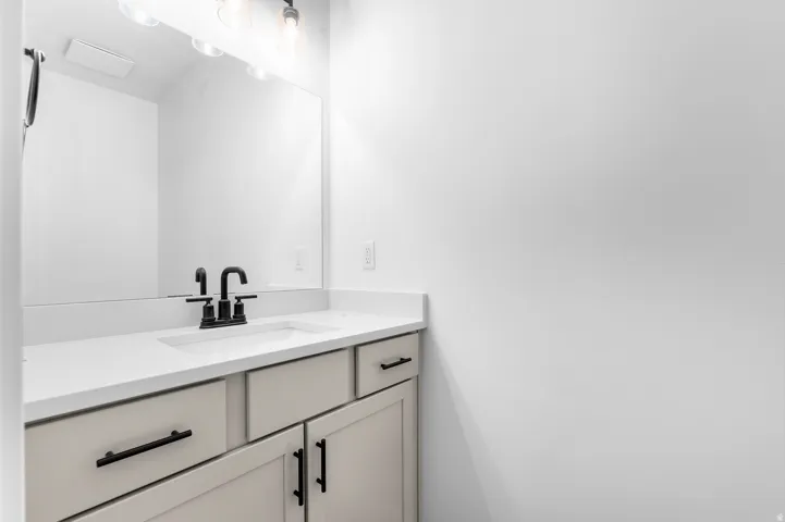 Integrated vanity with a rectangular basin, light-toned countertop, and matte black faucet