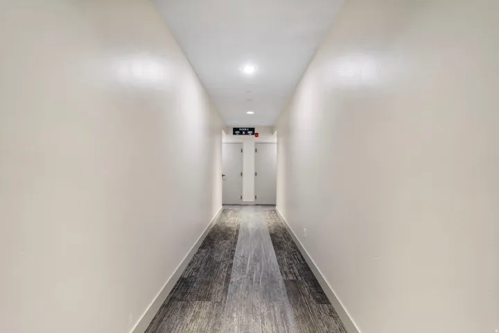 Hallway featuring light-toned walls, recessed lighting, and wood-finish flooring