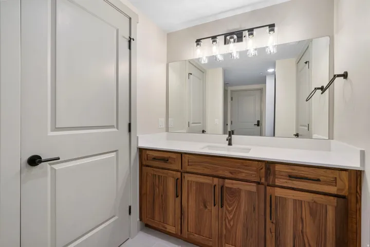 Bathroom vanity with wood-finish cabinetry, solid surface countertop, and undermount sink
