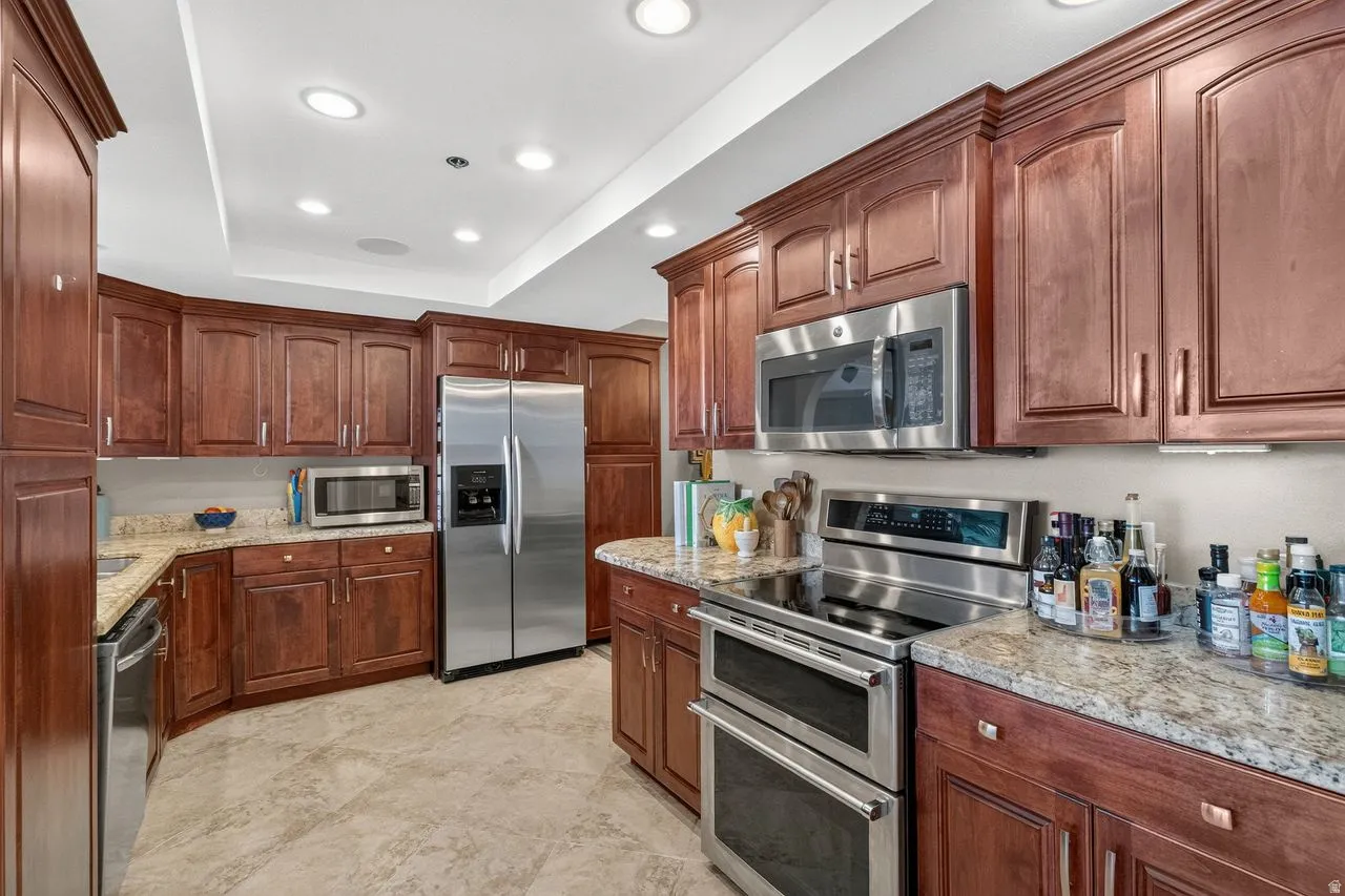 Kitchen featuring extensive wood cabinetry, granite countertops, and stainless steel appliances including a double oven range, built-in microwave, and side-by-side refrigerator
