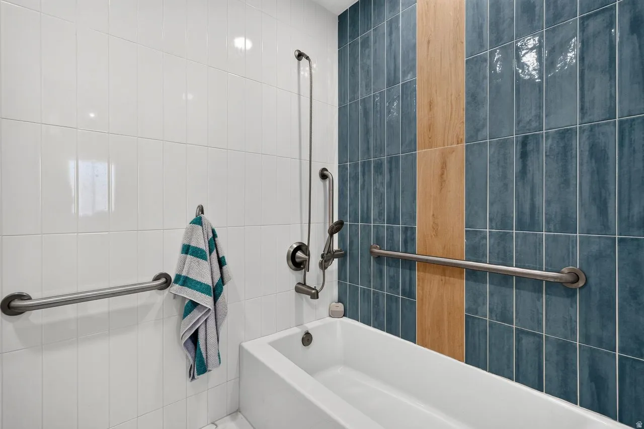 Soaking tub with white subway tile and blue vertical tile accents