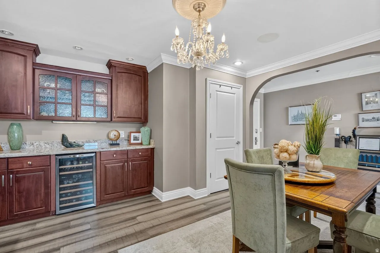 Wet bar with wood cabinetry, granite countertop, glass-front upper cabinets, and an integrated beverage refrigerator
