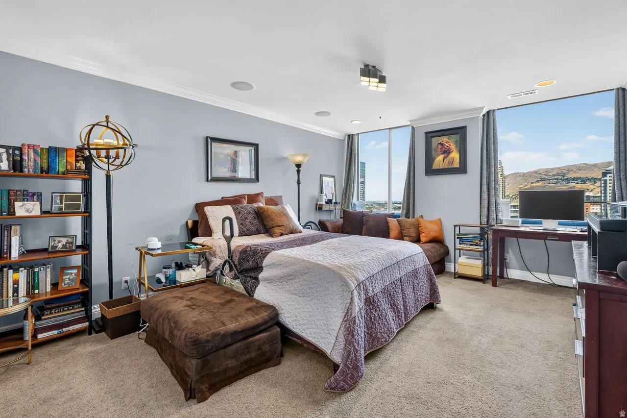 Expansive room featuring large windows, crown molding, and neutral carpet flooring